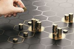 a person placing coins on top of each other in front of a board game design