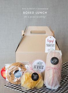 an open box with some food in it sitting on a checkered table cloth next to a bag