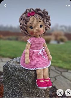 a crocheted doll sitting on top of a rock