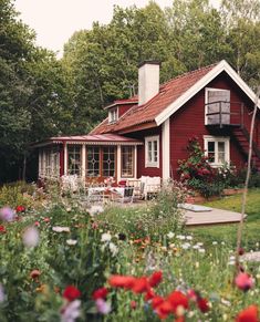 a red house surrounded by flowers and trees