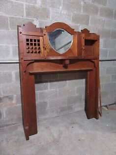 an old wooden table with a mirror on it's top and bottom shelf, in front of a brick wall