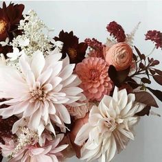 a vase filled with lots of flowers on top of a white table next to a wall