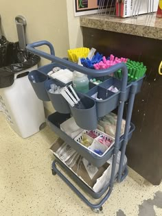 a cart filled with lots of different types of toothbrushes and other items next to a trash can