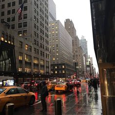 a city street filled with lots of traffic and people walking on the sidewalk near tall buildings