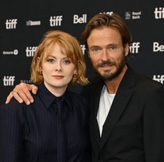 a man and woman posing for the camera at a red carpeted event, with one holding his arm around the other's shoulder