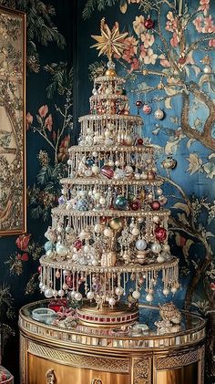 a christmas tree is sitting on top of a gold table in front of a wall