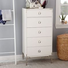 a white chest of drawers sitting next to a window