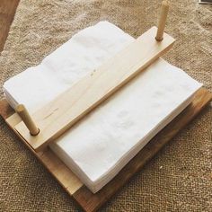 two white towels are sitting on a wooden tray with a rolling pin in the middle