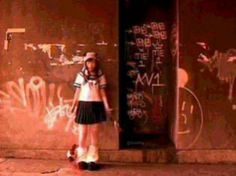 a girl standing in front of a wall with graffiti on it