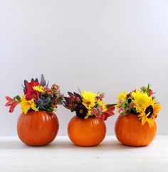 three pumpkin shaped vases with flowers in them