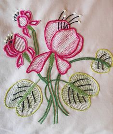 a close up of a flower on a white cloth with green and pink trimmings