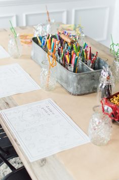 a wooden table topped with lots of different colored markers and pencils on top of it