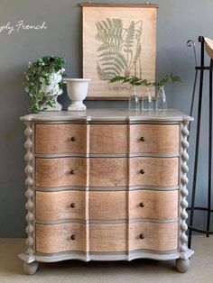 an old dresser has been decorated with plants and vases on the top, as well as a painting above it