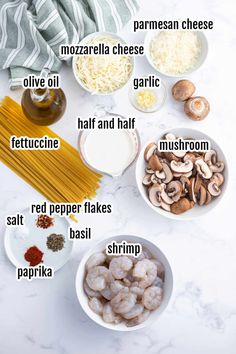 the ingredients to make shrimp pasta are shown in bowls on a marble countertop, including mushrooms, parmesan cheese, olive oil, garlic, fettuccine, and red pepper flakes