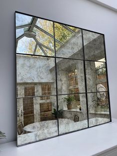 the reflection of a house in a mirrored wall mirror on a shelf next to a potted plant