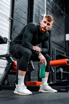 a man squatting on the ground holding a green object