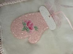 a pink and white teddy bear with a flower on it's head sitting on a lace doily