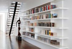 the bookshelves are full of books and there is a staircase in the background