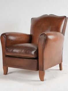 a brown leather chair sitting on top of a white floor