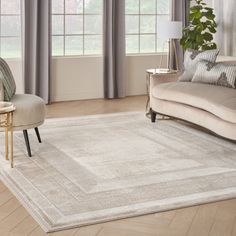 a living room area with a couch, chair and rug in front of two windows