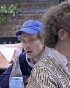 two people sitting next to each other in front of a table with water bottles on it