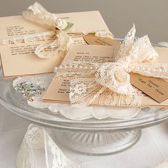 some cards are sitting on top of a glass plate with pearls and ribbons around them