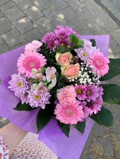 a bouquet of pink and white flowers sitting on top of a purple piece of paper