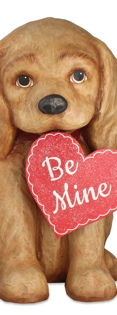 a brown dog holding a red heart with the words be mine written on it