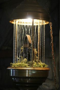 a clock with chains hanging from it's sides and a light shining on top