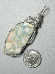 Rock Hill Jasper Pendant Wire Wrapped in .925 Sterling Silver Round Wire An abstract artistic kind of jasper displaying multiple pattern and unusual color variation, this stone consists of predominantly cream-white, beige-yellow, and light green in a random patchy pattern. Best with intricately mottled pattern clothing of similar or contrast color or style and gives the wearer a light, refreshing, cheerful presence. It wears fine with most colors especially light and bright, but may not match with dissimilar patterns such as stripes, blocks, geometric, etc.; very well suited with an artistic view due to colors, contrast, pattern, and some small natural surface cavities; a near standard rhombohedral shape and flat surface contour may provide some appeal to a purist view. Description: A mixe Earthy White Jewelry As A Gift, Artisan Ocean Jasper Jewelry As Gift, Artisan Ocean Jasper Jewelry For Gifts, Artisan Silver Jasper Jewelry, Artisan Jasper Jewelry In Oval Shape, Artisan Oval Jasper Jewelry, Elegant Silver Jasper Jewelry, Earthy Ocean Jasper Jewelry Gift, Nickel-free Jasper Jewelry For Gifts