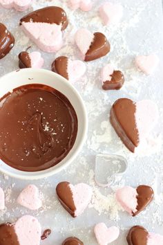 some heart shaped chocolates are in a bowl and on the table next to them