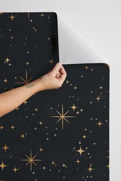 a person's hand on top of a black and gold star patterned mouse pad