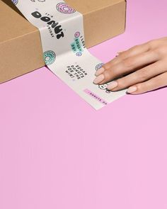 a woman's hand is holding a roll of sticker tape next to a box