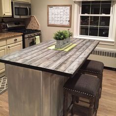 a kitchen island with two stools and a potted plant on top of it