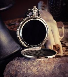 an antique pocket watch sitting on top of a rock