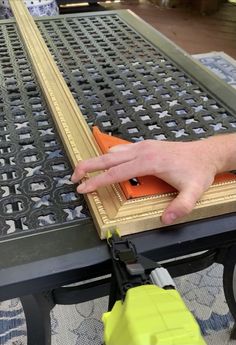 a person is using a yellow tool to clean the metal grate on a table