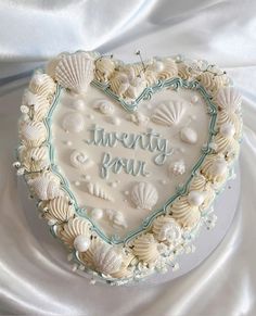 there is a heart shaped cake with shells on it and the words happy birthday written in frosting