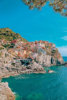 the ocean is blue and clear with houses on it's cliff side, along with some trees