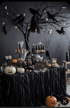 a table topped with lots of bottles and pumpkins next to a tree filled with halloween decorations