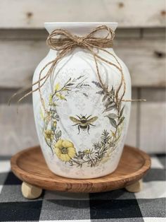 a white vase sitting on top of a wooden stand with a bow around it's neck