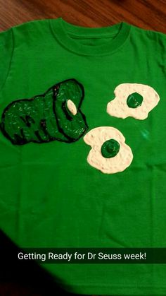 a green t - shirt with an image of two fried eggs on it and the words getting ready for dr seuss week