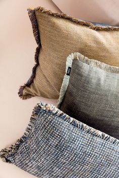 two pillows with frayed edges sit on a couch