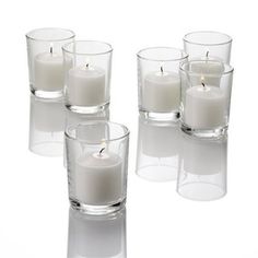 several clear glass vases filled with white candles