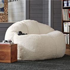 a white bean bag chair sitting on top of a wooden floor next to a book shelf