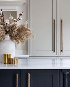 a vase filled with flowers sitting on top of a kitchen counter next to gold pulls