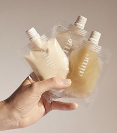 a hand holding three plastic bottles filled with liquid