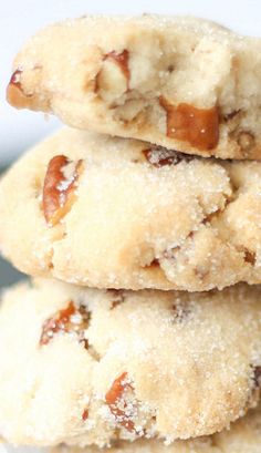 three cookies stacked on top of each other in front of a white plate filled with nuts