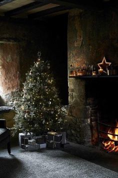 a living room with a lit christmas tree in the corner next to a fire place