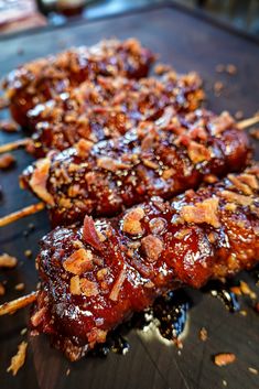 two pieces of meat on skewers covered in sauce and chopped pineapples