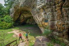 two people standing in front of a large rock formation